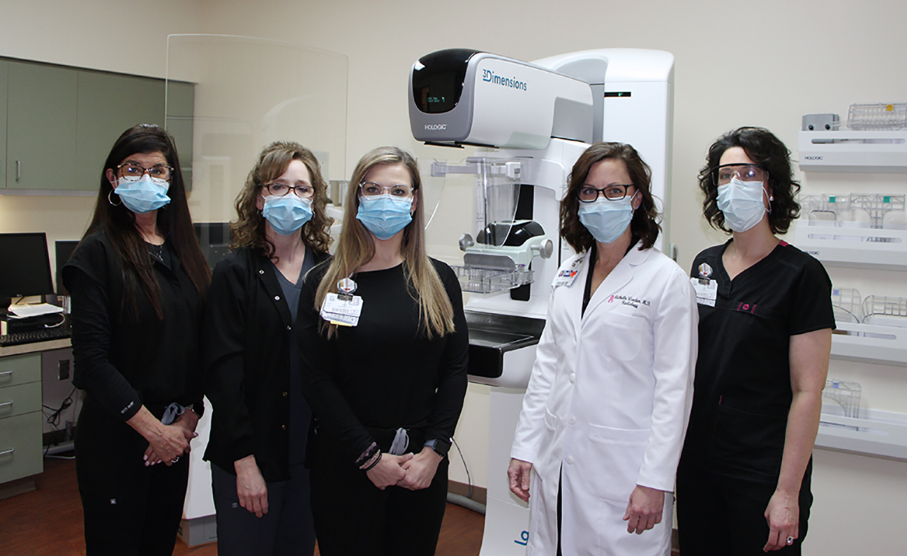 Mammography team standing in front of the 3D Mammography Machine